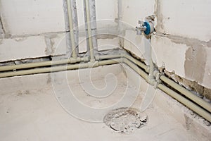 A close-up on a bathroom plumbing system, including network of water supply pipes, drain pipes and toilet closet flange of a drain