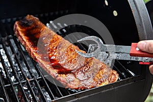 Close-up Of BBQ Roast and Smoked Pork Spareribs glazed with sauze On The Hot Charcoal Grill With Flames, Barbecue and