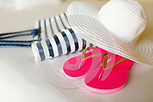 Close-up of beach bag, hat and flip-flops on bed