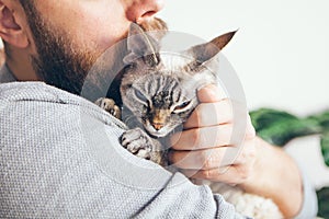 Close-up of beard man who holds his cute purring Devon Rex cat.