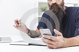 Close up of bearded hipster`s hand holding a smartphone