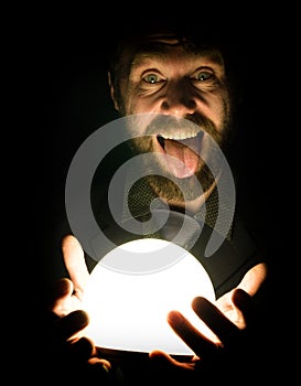 Close-up of a bearded man expresses various emotions on a black background, holding a lamp in front of himsalf