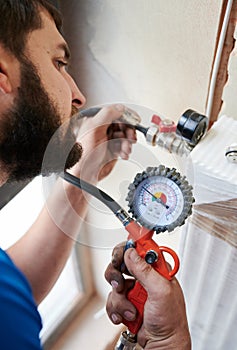Male plumber checking gas tightness of heating system. photo