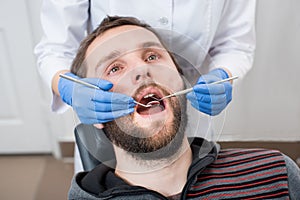 Close up of bearded man having dental check up in dental clinic
