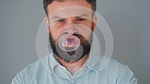 Close-up of a bearded man`s mouth chewing chewing gum. Man blowing out a bubble of bubble gum