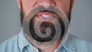 Close-up of a bearded man's mouth chewing chewing gum. Man blowing out a bubble of bubble gum