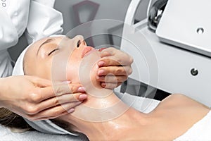 Close-up beautician doctor hand making anti-age procedure, mask and peeling for young attractive female client at beauty