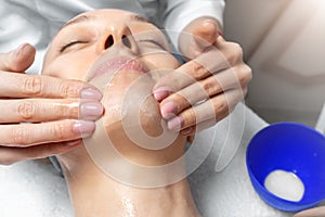 Close-up beautician doctor hand making anti-age procedure, mask and peeling for young attractive female client at beauty