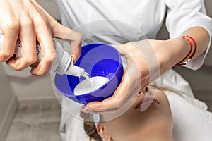 Close-up beautician doctor hand pouring white liquid peeling acid for anti-age procedure mask peel for young attractive