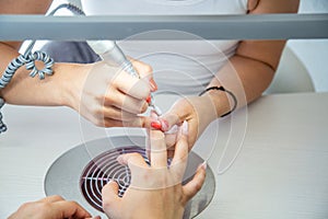 Close up of Beautician with Electric Nail Drill in Beauty Manicure Salon