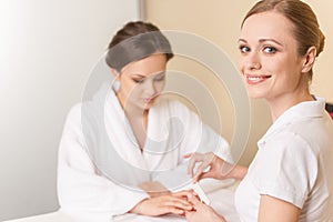 Close-up of beautician hand filing nails of woman in salon.