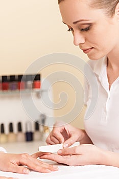 Close-up Of Beautician Hand Filing Nails Of Woman In Salon.