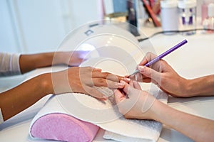 Close-up of beautician painting a woman`s nails with a brush in photo