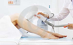 Close up of beautician removing hair on lady leg with laser epilation machine