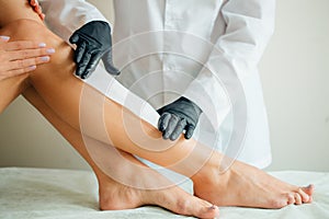 Close-up Of A Beautician Waxing Woman Leg With Wax Strip At Beauty Spa