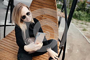 Close-up Beautiful 30-year-old woman with glasses is texting and taking selfies on a smartphone camera in a park