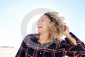 Close up beautiful african american woman laughing with hand in hair outdoors
