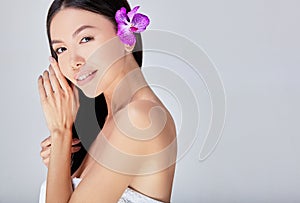 Close-up, beautiful Asian woman with bare shoulders and a flower in her hair