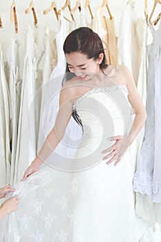 Close up of a beautiful Asian woman fitting wedding dress. Smiling and happy