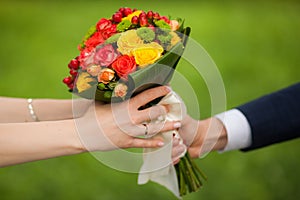 Close up of beautiful bouquet of fresh flowers. man and woman hands. happy bride, groom over summer green park background.