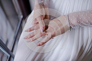 Close-up of beautiful bride's hands, perfectly manicured, with focus on the delicate solitaire engagement ring