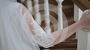 Close up of Beautiful Bride walking down stairs. Woman in white dress comes down the stairs. Slow motion