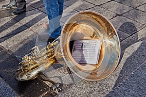 Close-up of a beautiful and bright tuba resting on the floor with the score of the song in the square of Zocodover