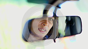 Close-up Of beautiful brunette woman, artist, sitting in the car, looking in the rear view mirror. she straightens her