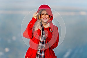 Close up beautiful Caucasian woman stand near cliff with hold coat hood and stay on the mountain with warm light of sun rise and