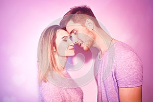 Close-up of beautiful couple kissing. Happy man and girl touching with their noses in pink background. Portrait of a loving