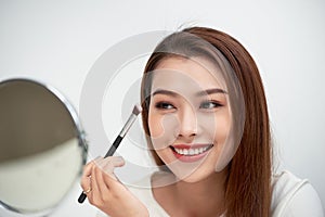 Close up of beautiful face of asian young woman getting make-up. Asian woman is applying eyeshadow on her eyebrow with brush.