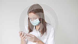 Close-up of a beautiful female doctor in a mask on her face with a mobile phone in her hands