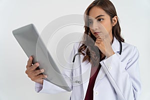 close up of beautiful female doctor thinking while looking at pad screen with hand holding chin