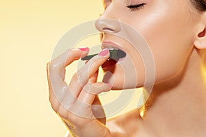 Close up of beautiful female face with cucumber slice over yellow background. Cosmetics and makeup, natural and eco