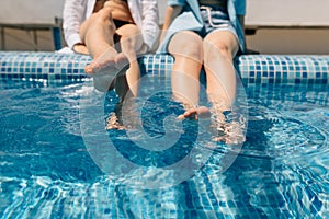 close-up of beautiful female legs in the swimming pool. Girlfriends girls swing their feet on the water in the pool. The