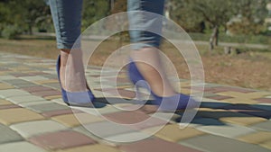 Close-up of beautiful female legs in trendy high heel shoes stepping on pavement