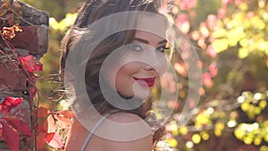 Close-up of a beautiful girl with bright make-up in autumn park.