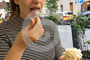 Close up of beautiful girl face of caucasian girl with red hair and open mouth eating ice cream as a dessert from cone with