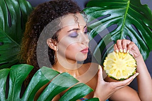 Close-up of beautiful girl with pineapple posing in tropical forest