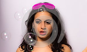 Close up of a beautiful girl with professional make-up blowing soap bubbles around her