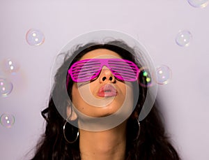 Close up of a beautiful girl with professional make-up blowing soap bubbles around her