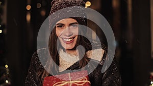 Close Up of Beautiful Girl in Winter Clothes Holding Red Present Box, Looking Happy and Smiling, Looking to Camera