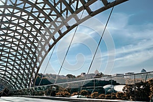 A close-up of a beautiful glass-and-steel footbridge with a glass roof. Against the background of the historical part of the city