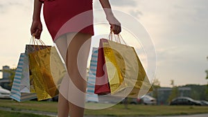 Close-up beautiful legs of young shopping woman female in red dress with bags packages