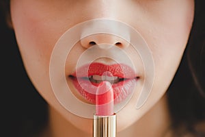 Close up beautiful luxury young woman applying lip liner to nude red lips