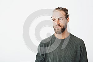 Close up of beautiful manly guy with light hair, fashionable hair and beard in grey shirt smiling and looking aside with