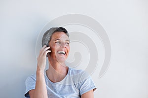 Close up beautiful middle age woman talking on mobile phone against white wall