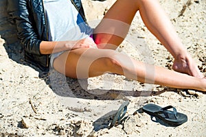 Close up of beautiful model`s legs on a beach girl wears leather