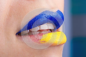 Close up of beautiful and plump female lips painted in blue and yellow. Lips of woman painted in Ukrainian flag colors.