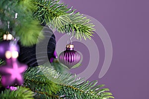 Close up of beautiful purple riffled glass tree bauble on decorated Christmas tree with other seasonal tree ornaments